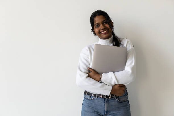 istock Pretty Indian young woman using laptop standing against white background 1904982262