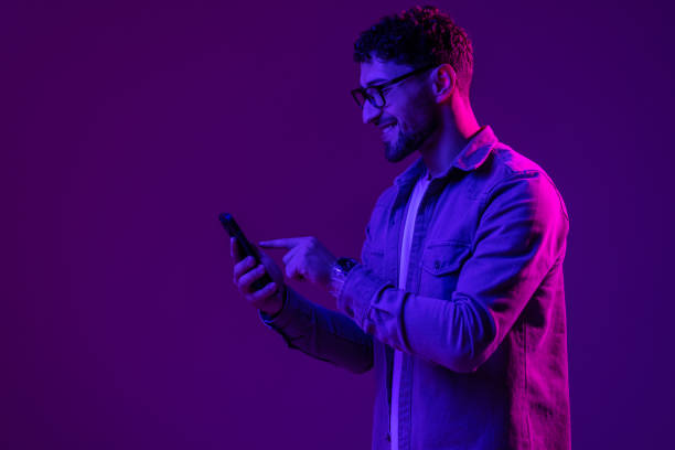 istock Man with phone use smartphone online, video call and selfies on mixed neon light 1905019697