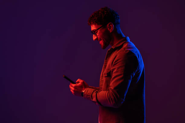 istock Male with smartphone on Red and blue neon light 1905026615