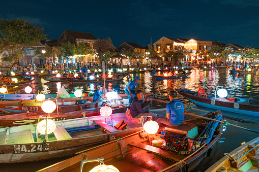 Hoi An, Vietnam - November 11, 2022: Hoi An at dusk with boats cruising on river side with lantern.