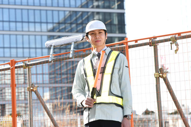istock A young Asian man wearing work clothes and a helmet is working as a traffic controller while holding a guide light at a construction site. 1905032343