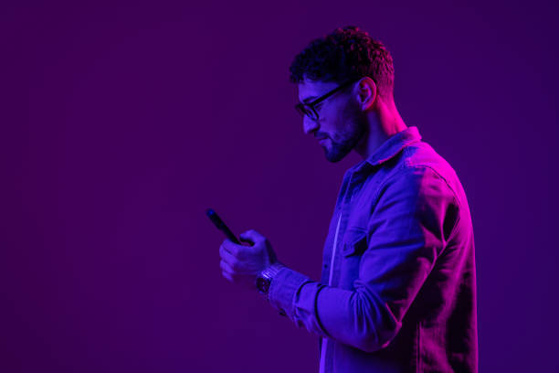 istock Man with phone use smartphone online, video call and selfies on mixed neon light 1905045542