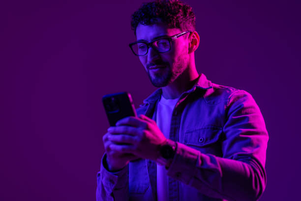 Man with phone use smartphone online, video call and selfies on mixed neon light
