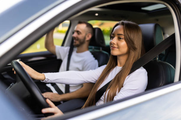 istock Beautiful young couple sitting on the front passenger seats and smiling while handsome man driving a car 1905070726