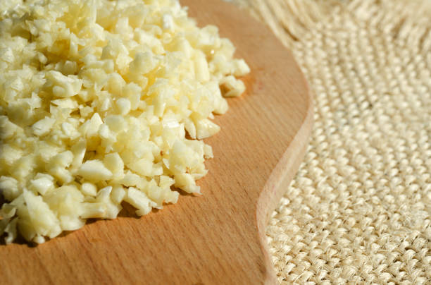 istock Sliced garlic on a wooden cutting board on a burlap background. 1905124377