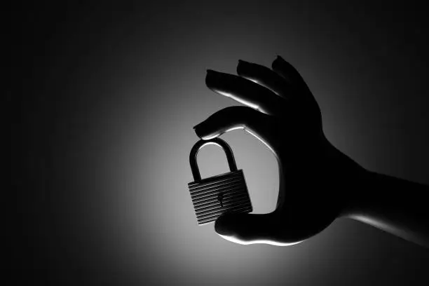 Photo of Hand holding a padlock in silhouette. Illustration of the concept of online security