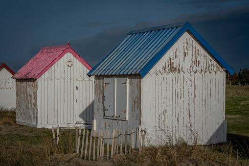 View of colorful bathing wooden cabins of Gouville on the dunes