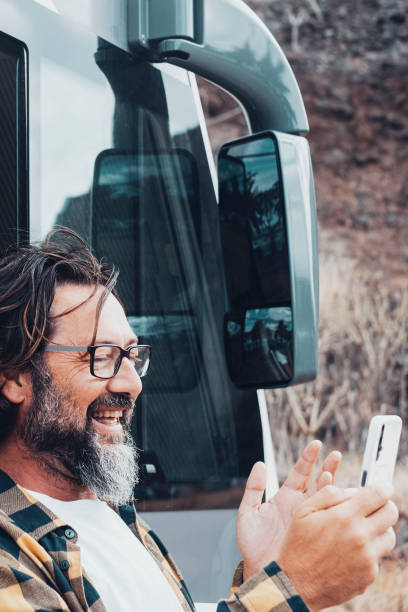istock One man doing video call web using mobile phone agains a camper van vehicle. Concept of people and alternative travel vacation with motor home. Outdoor roaming connection smartphone. People tourist 1905156601