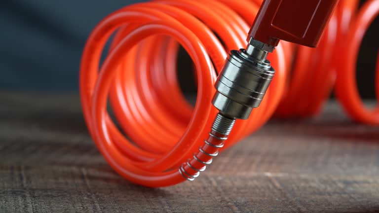 Worker connects orange air hose to air blow gun via hose coupling, close up