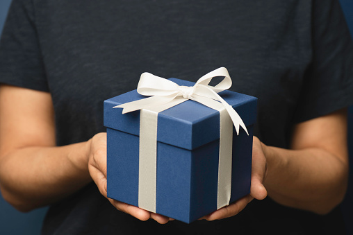 Hands holding a blue gift box.