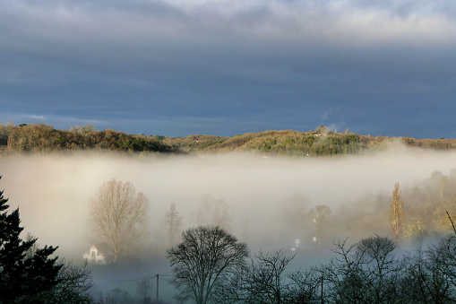Sun burning through the early morning mist in Autumn in the Dordogne, France