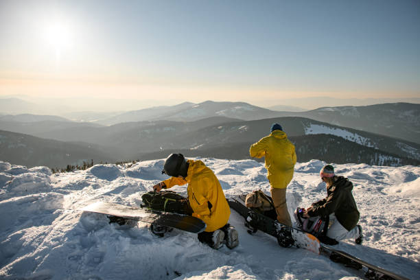 istock Skiers unpacking backpacks and preparing equipment for skiing down snow-covered slopes of winter mountains 1905224152