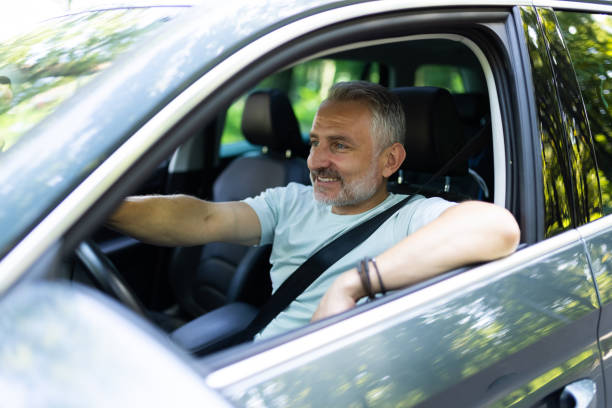 istock Middle aged man driving a car in city 1905225307