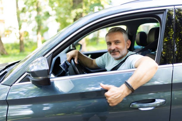 istock Middle age man make selfie by camera doing ok gesture while drive car at street 1905227427