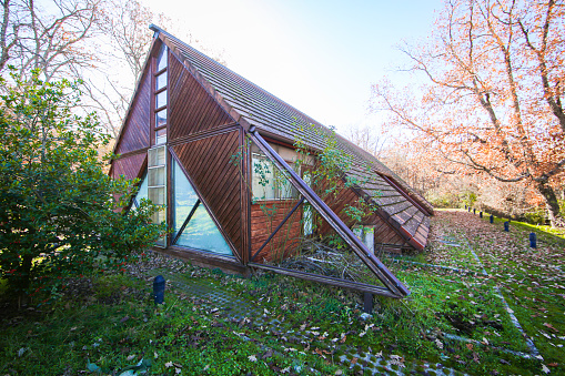Sustainable architecture with greenhouses and orchards. Triangular timber facades.