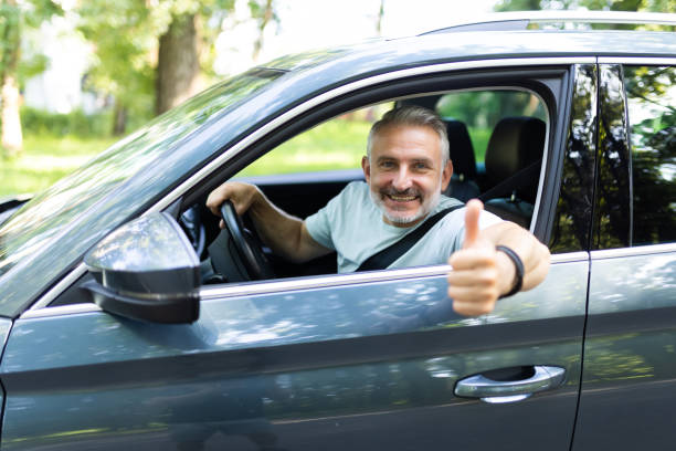istock Middle age man make selfie by camera doing ok gesture while drive car at street 1905235287