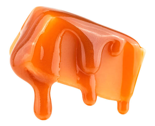 istock Caramel sauce flowing on caramel candy, isolated on a white background. Levitating caramel candy. 1905235290