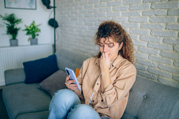 istock Depressed woman sitting on sofa with mobile phone 1905274121