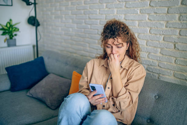 istock Depressed woman sitting on sofa with mobile phone 1905274632