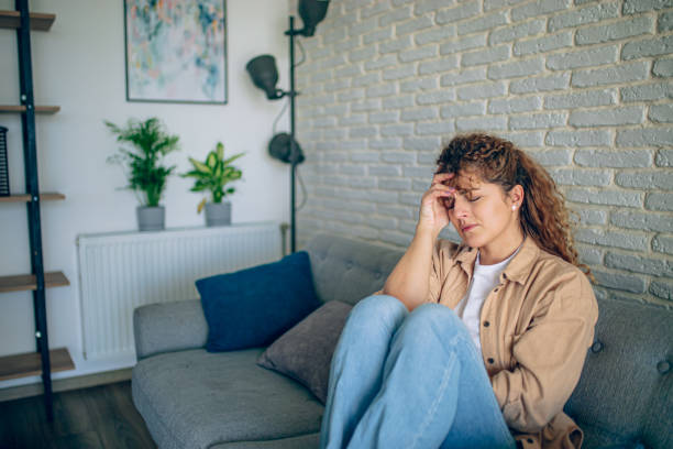 istock Young woman having a headache on a sofa at home 1905276184