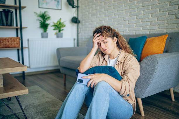 istock Depressed woman sitting on floor with mobile phone 1905282848