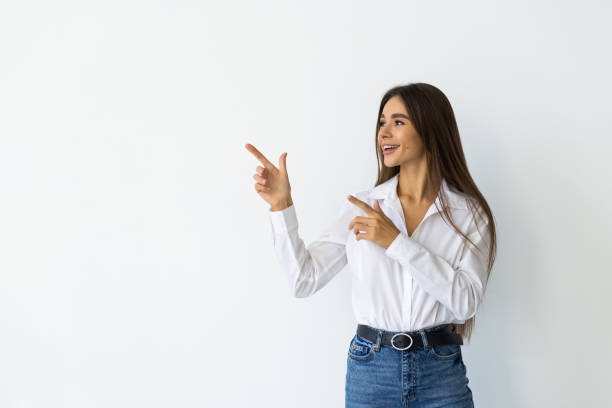 istock Smiling young woman pointing finger side isolated on white background 1905288996