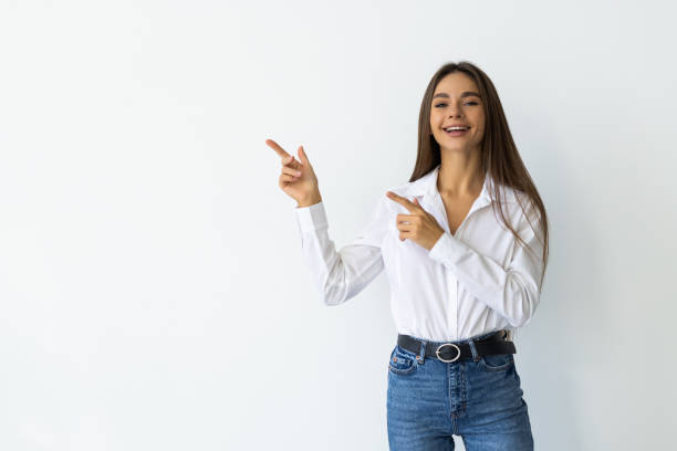 istock Smiling young woman pointing finger side isolated on white background 1905289524