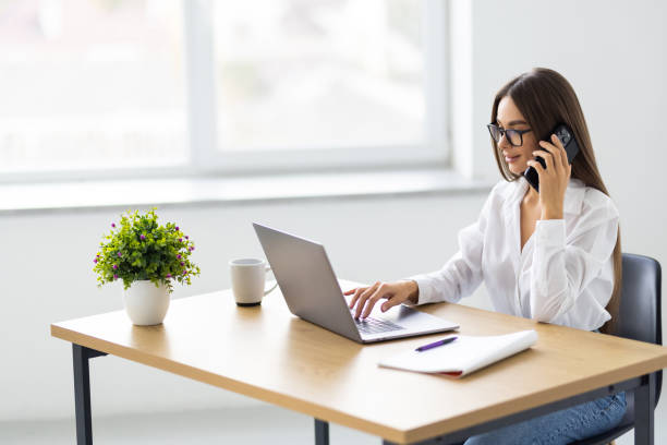 istock Happy young woman i calling her friend, talking and asking about something, using laptop in office 1905295750