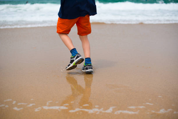 istock Kid in orange shorts playing on a beach.. 1905360851