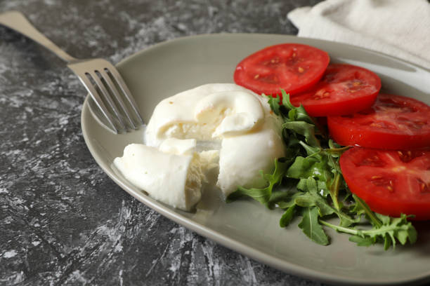 istock Delicious burrata cheese with tomatoes, arugula and fork on grey table, closeup 1905373760