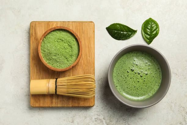 istock Cup of fresh matcha tea, green powder and bamboo whisk on light grey table, flat lay 1905379926