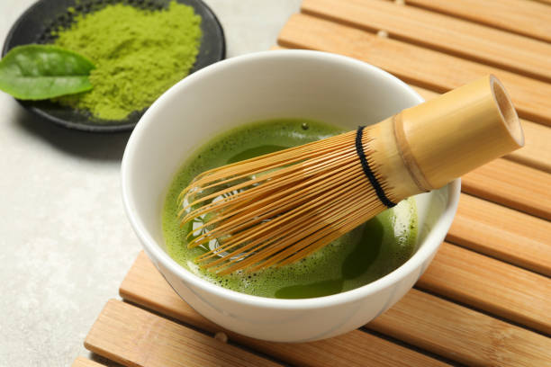 istock Cup of fresh matcha tea with bamboo whisk on light grey table, closeup 1905382003