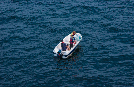 Lindesnes, Norway - July 06 2006: Three persons in s small boat inspecting a crab cage.