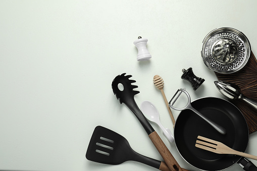 Set of different kitchen utensils on white table, flat lay. Space for text