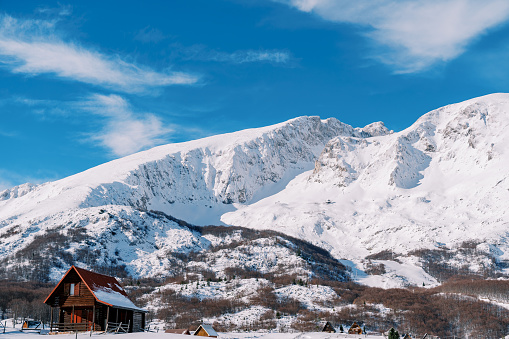 Secluded wooden cottage in a small snowy village at the foot of the mountains. High quality photo