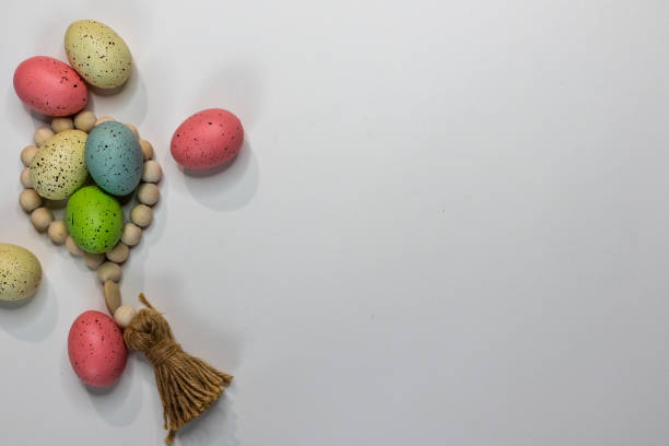 Springtime multicolor Easter eggs with wood bead tassel on white background and copy space