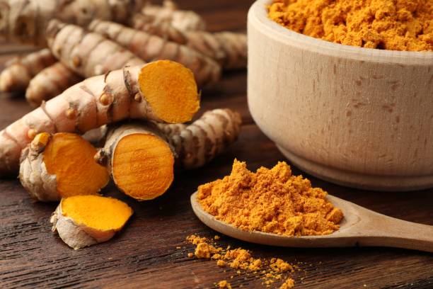 istock Aromatic turmeric powder and raw roots on wooden table, closeup 1905450593