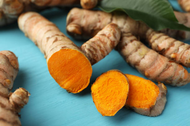 istock Whole and cut turmeric roots on light blue wooden table, closeup 1905451677