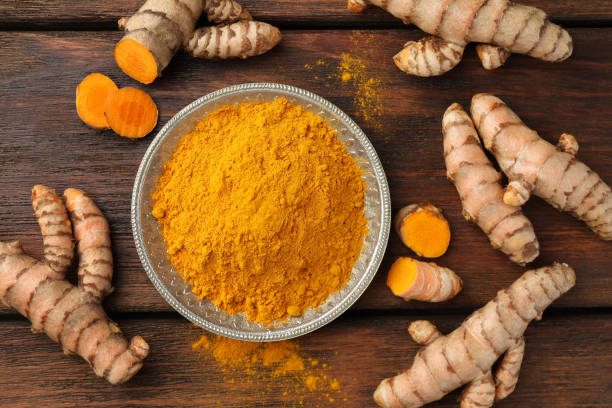 istock Plate with aromatic turmeric powder and cut roots on wooden table, flat lay 1905455298