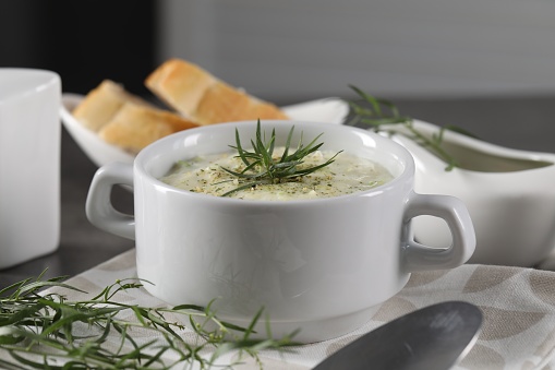 Delicious cream soup with tarragon, spices and potato in bowl on table, closeup
