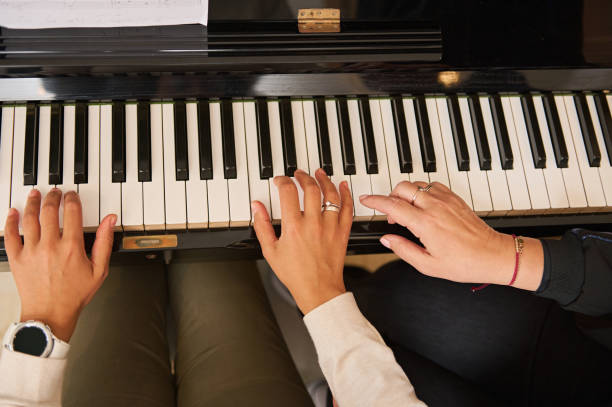 istock Young woman with student playing piano, above view. Music lesson 1905469113