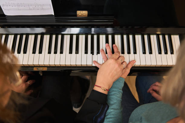 istock View from above women holding hands, performing classical musical composition, feeling rhythm while play grand piano 1905475849
