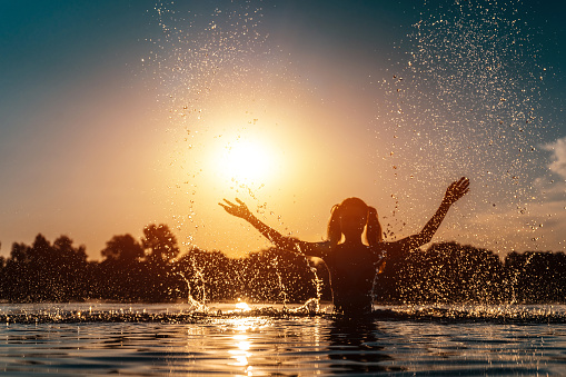 joyful girl splash and swimming in lake on beach outdoor at sunny day