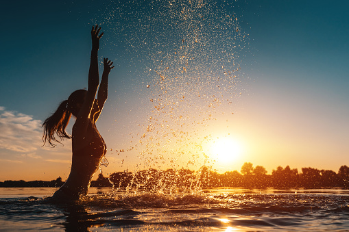 joyful girl splash and swimming in lake on beach outdoor at sunny day