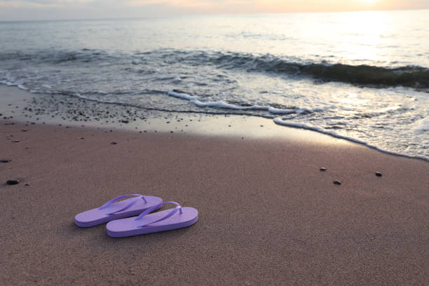 Flip-flops on beach in front of woman