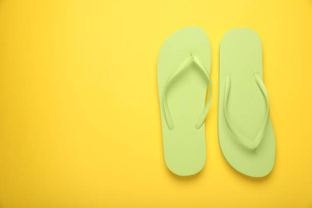 istock Stylish light green flip flops on yellow background, top view. Space for text 1905515651