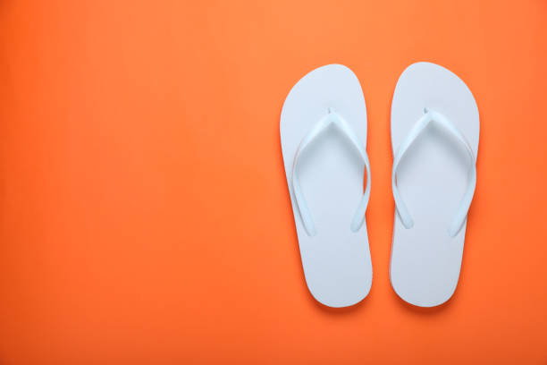 istock Stylish white flip flops on orange background, top view. Space for text 1905516177