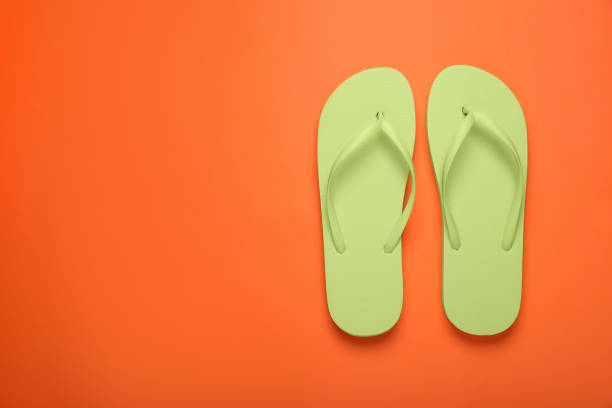 istock Stylish light green flip flops on orange background, top view. Space for text 1905516182