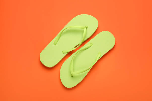 istock Stylish light green flip flops on orange background, top view 1905516189