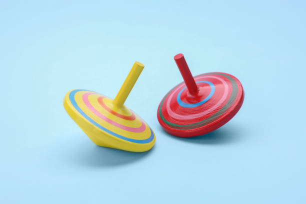 istock Two bright spinning tops on light blue background. Toy whirligig 1905539947
